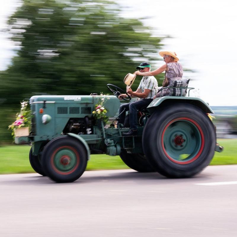 Brautpaar fährt auf einem geschmückten Oldtimer-Traktor